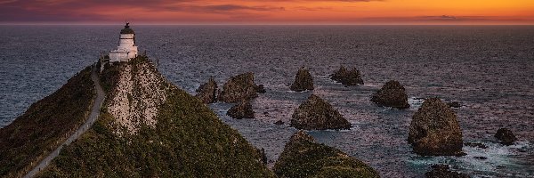 Nowa Zelandia, Latarnia morska, Nugget Point Lighthouse, Zachód słońca, Morze, Chmury, Skały