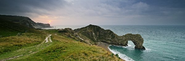 Chmury, Trawa, Wybrzeże Jurajskie, Durdle Door, Łuk wapienny, Anglia, Hrabstwo Dorset, Skały, Zachód słońca